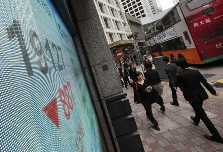 People walk past a panel displaying the blue-chip Hang Seng Index outside a branch of China Construction Bank in Hong Kong November 10, 2011