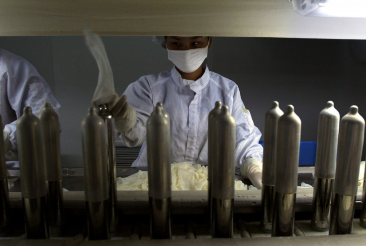 A worker at the factory of Chinese condom manufacturer Safedom places condoms onto a production line belt in Zhaoyuan