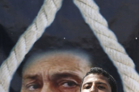 An anti-Mubarak protester shouts slogans in front of a poster depicting Mubarak with a noose in Cairo