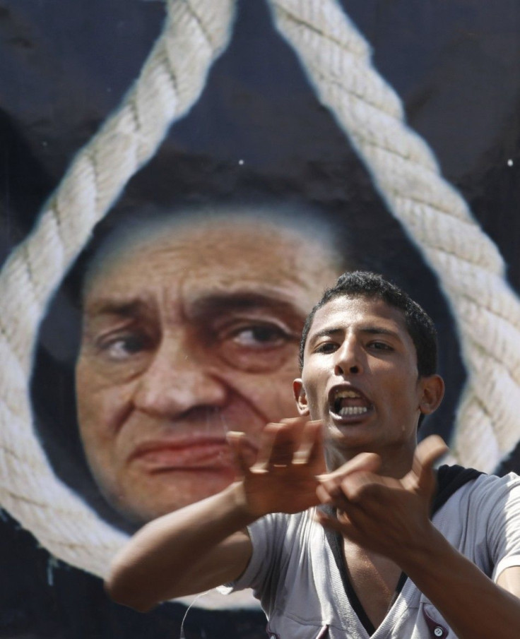 An anti-Mubarak protester shouts slogans in front of a poster depicting Mubarak with a noose in Cairo