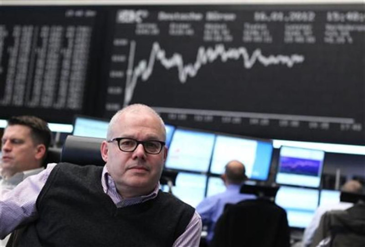 Traders work at their desks in front of the DAX board at the Frankfurt stock exchange