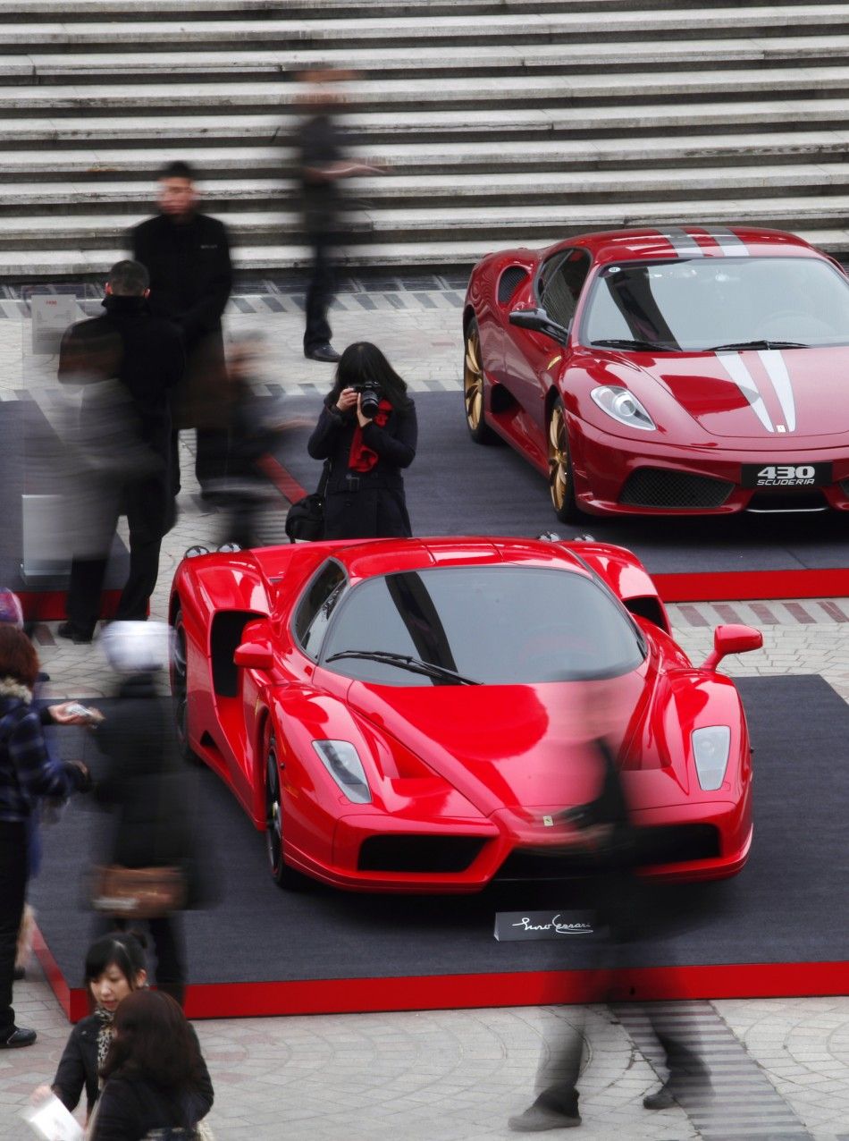 A woman takes pictures as people walk past an Enzo Ferrari C during an exhibition held to celebrate Ferrari039s 999th car sold in China from 2004 to 2010, at the Oriental Pearl Tower in Shanghai January 14, 2011.