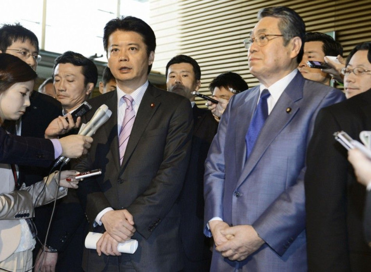 Japan&#039;s Foreign Minister Gemba, flanked by Defence Minister Tanaka, is surrounded by reporters in Tokyo.