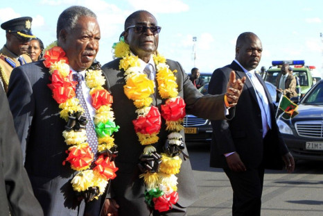 Zimbabwe President Robert Mugabe walks with Zambian President Michael Sata as he arrives for the Zimbabwe International Trade Fair (ZITF)
