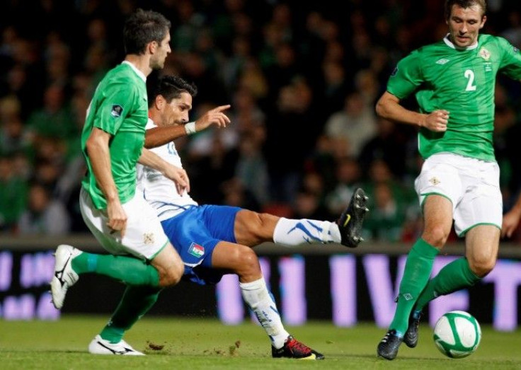 Italy's Borriello kicks the ball as Hughes and McAuley of Northern Ireland watch during their Euro 2012 qualifying soccer match at Windsor Park stadium, in Belfast