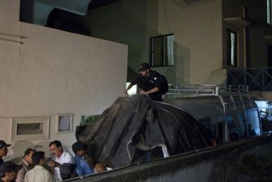 Policemen cover the vehicle carrying the family members of Osama Bin Laden with cloth to avoid the media before they leave for the airport in Islamabad