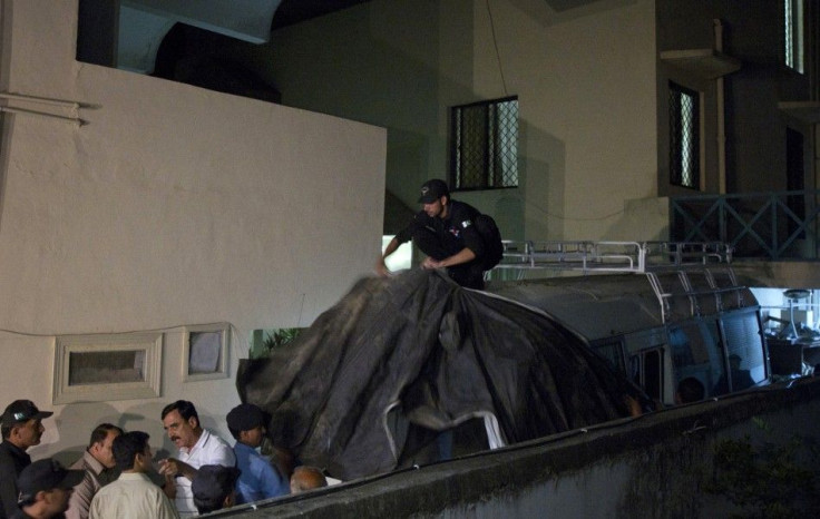 Policemen cover the vehicle carrying the family members of Osama Bin Laden with cloth to avoid the media before they leave for the airport in Islamabad