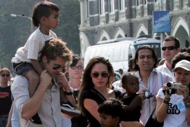 Hollywood star Pitt carries adopted son Maddox as Jolie carries adopted daughter Zahara during their stroll outside their hotel in Mumbai