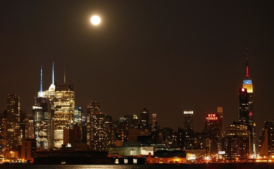 A full moon rises above the skyscrapers in Times Square and the Empire State Building in New York