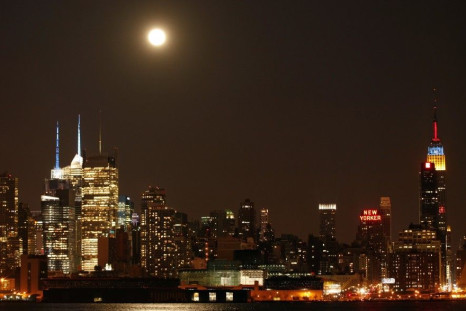 A full moon rises above the skyscrapers in Times Square and the Empire State Building in New York