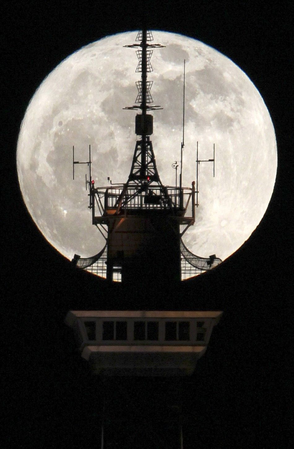 The moon is seen behind the top of the radio and television tower Funkturm in Berlin
