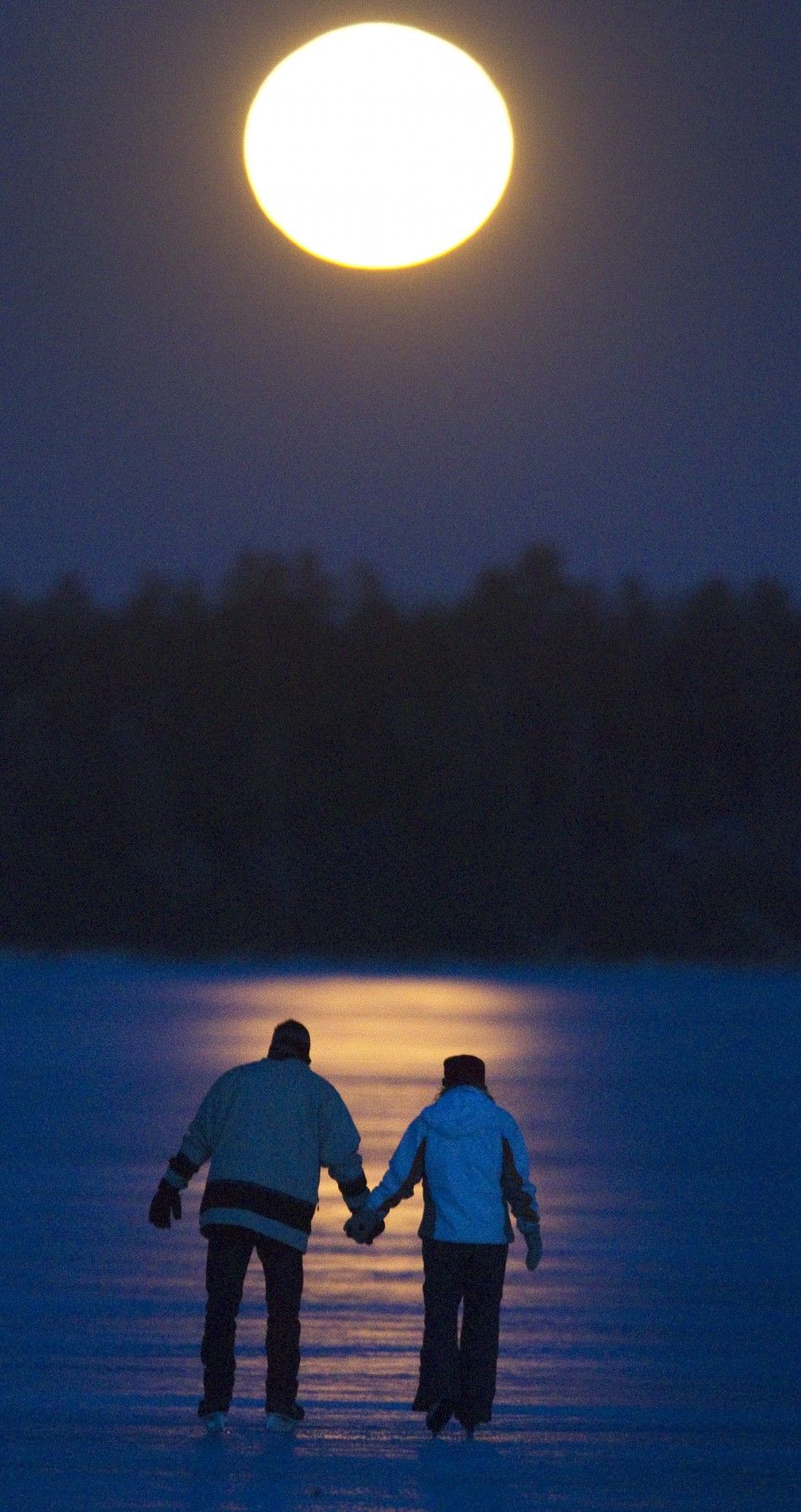 Greg Kerr and Allie Mahoney skate under a full moon on Pigeon Lake near Bobcayeon Ontario