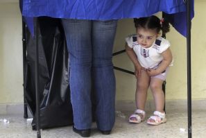 A girl peers under a polling booth during Greek elections in Athens