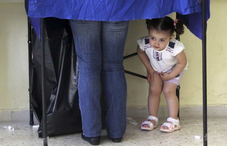 A girl peers under a polling booth during Greek elections in Athens