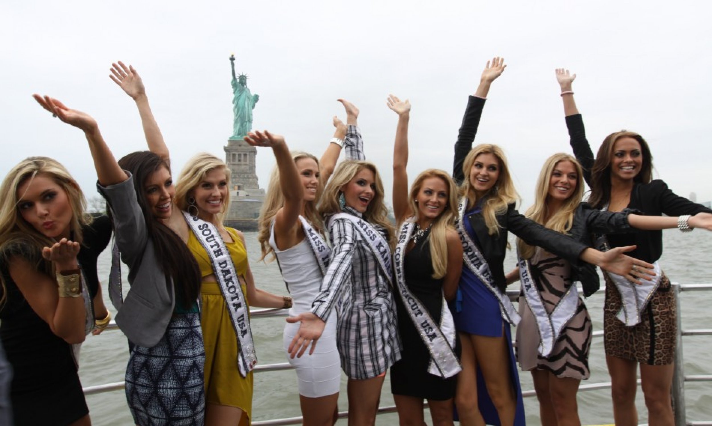 Several Miss USA contestants pose for an iconic photo in front of the Statue of Liberty