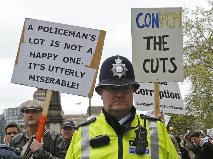 A policeman keeps watch on off-duty police officers as they march in protest at funding cuts through central London