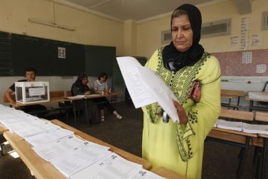A woman collects ballots during parliamentary elections at a polling station on the outskirts of Algiers