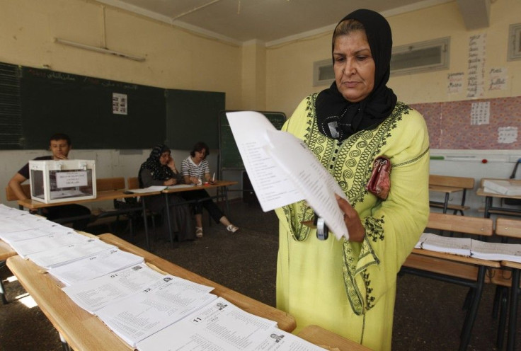 A woman collects ballots during parliamentary elections at a polling station on the outskirts of Algiers