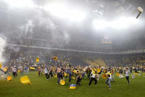 Fenerbahce fans invaded the pitch and threw plastic chairs and flares at police and Galatasary players.