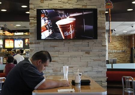 Customer Steven Price sits at a table near a HDTV screen showing the new McDonald's Channel featuring a commerical about McCafe drinks at a McDonald's restaurant, part of the test market for the channel in Norwalk, California