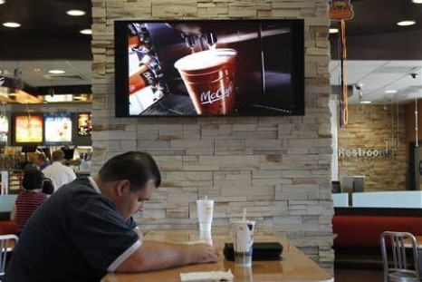 Customer Steven Price sits at a table near a HDTV screen showing the new McDonald&#039;s Channel featuring a commerical about McCafe drinks at a McDonald&#039;s restaurant, part of the test market for the channel in Norwalk, California