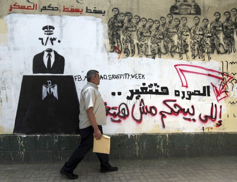 An Egyptian man walks in front of a wall sprayed with graffiti depicting the ruling military council controlling the presidential elections near Tahrir Square in downtown Cairo May 16, 2012. Voting starts in Egypt039s presidential election on May 23-24