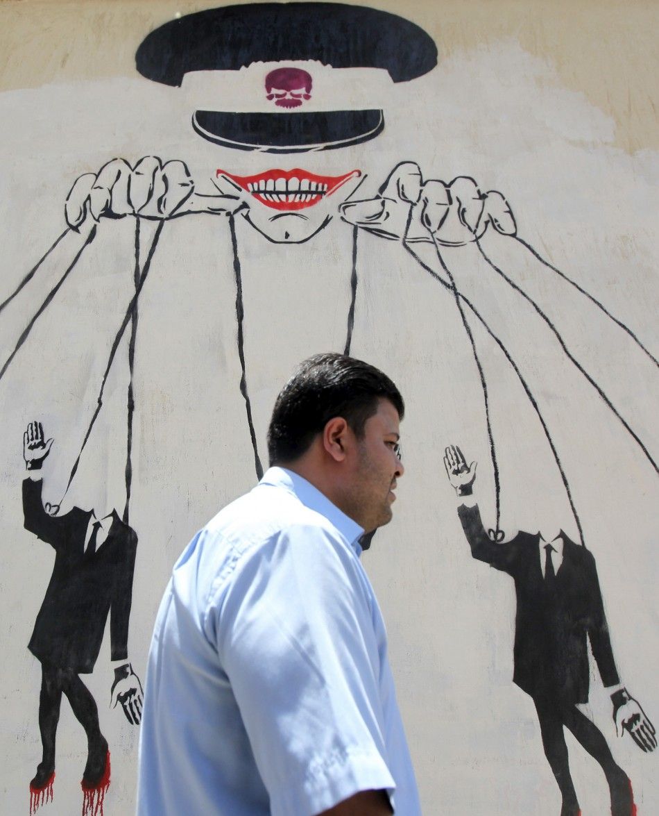 An Egyptian man walks in front of a wall sprayed with graffiti, depicting the ruling military council controlling the presidential elections as a puppet show, near Tahrir Square in downtown Cairo May 16, 2012. Voting starts in Egypt039s presidential el