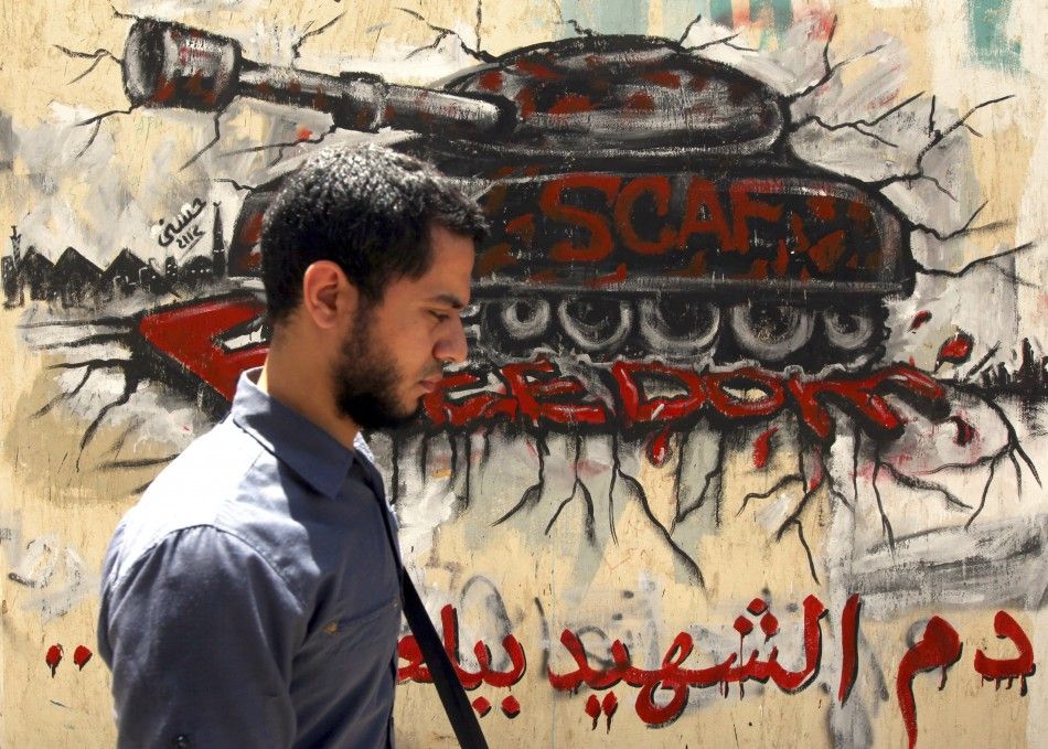 An Egyptian man walks in front of a wall sprayed with graffiti depicting a tank, as a protest against the ruling Supreme Council of the Armed Forces SCAF, near Tahrir Square in downtown Cairo May 16, 2012. 
