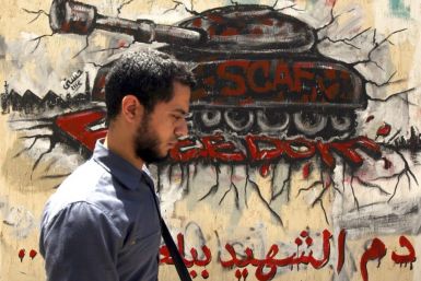 An Egyptian man walks in front of a wall sprayed with graffiti depicting a tank, as a protest against the ruling Supreme Council of the Armed Forces (SCAF), near Tahrir Square in downtown Cairo May 16, 2012. 