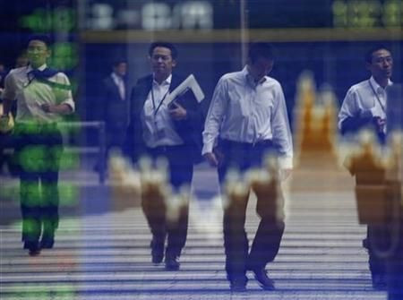 Pedestrians are reflected in a screen displaying the stock index prices in Tokyo