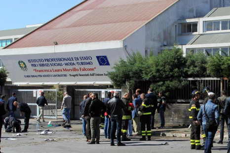Italian policemen and fire fighters inspect in front of the school where a bomb exploded in the southern Italian town of Brindisi
