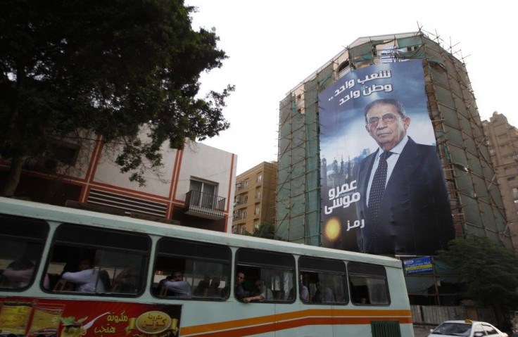 A bus passes by a giant campaign poster of presidential candidate Amr Moussa in Cairo