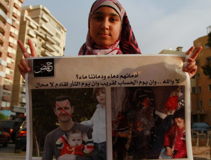 A Syrian refugee girl poses with a placard depicting Syria&#039;s President Bashar al-Assad with his children (L) and children who protesters say were killed by government security forces during a protest in Tripoli, northern Lebanon, May 26, 2012, agains