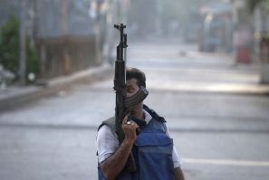 A plainclothes policeman holds a weapon as he walks down the streets during a firefight with gang members in Karachi.