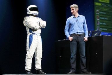 Craig Federighi, Apple Senior Vice President, Software Engineering stands on stage with a man in a racing suit, AKA, Fake Stig, to demo Racer OS X during the Apple Worldwide Developers Conference 2012 in San Francisco