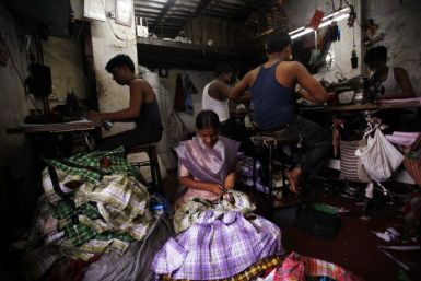 Fifteen-year-old Saira (C) cuts shirt threads inside a garment factory in Mumbai August 3, 2010.  