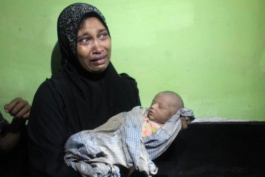 Amena Akter, a Rohingya from Myanmar, cries as she holds her 6-day-old son, Sangram, in the office of the Bangladesh Coast guard in Teknaf