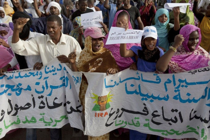 A man runs from tear gas fired by police during an anti-slavery demonstration in the main market of Nouakchott