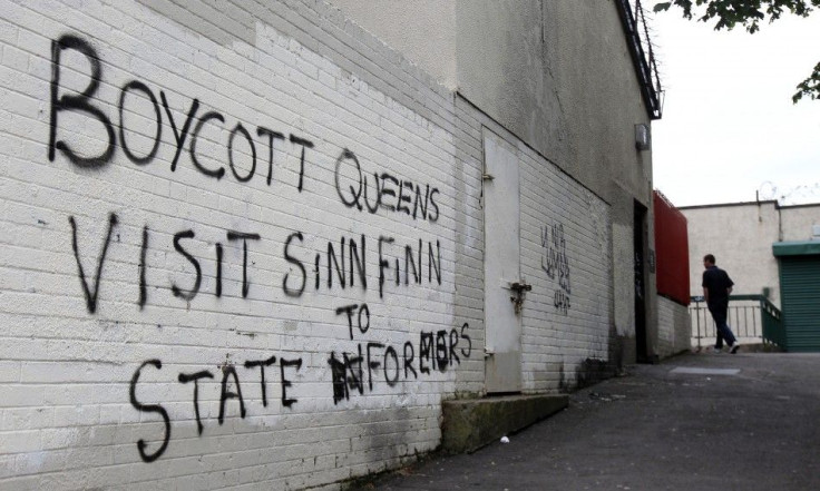 A man walks past graffitti painted on a wall in a nationalist area of north Belfast during Britain&#039;s Queen Elizabeth&#039;s two day tour of Northern Ireland