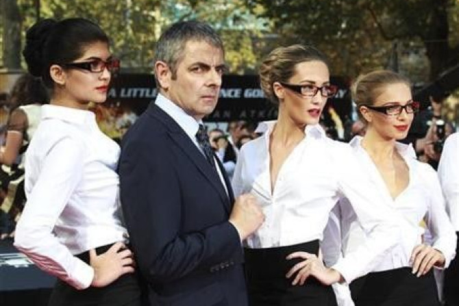 Actor Rowan Atkinson poses for a photograph with models as he arrives for the UK premiere of Johnny English Reborn, at the Empire Leicester Square in central London