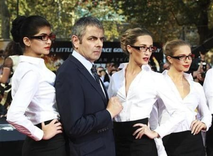 Actor Rowan Atkinson poses for a photograph with models as he arrives for the UK premiere of Johnny English Reborn, at the Empire Leicester Square in central London