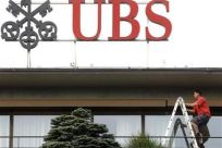 A worker climbs on a ladder under the logo of Swiss bank UBS at the company&#039;s headquarters in Zurich