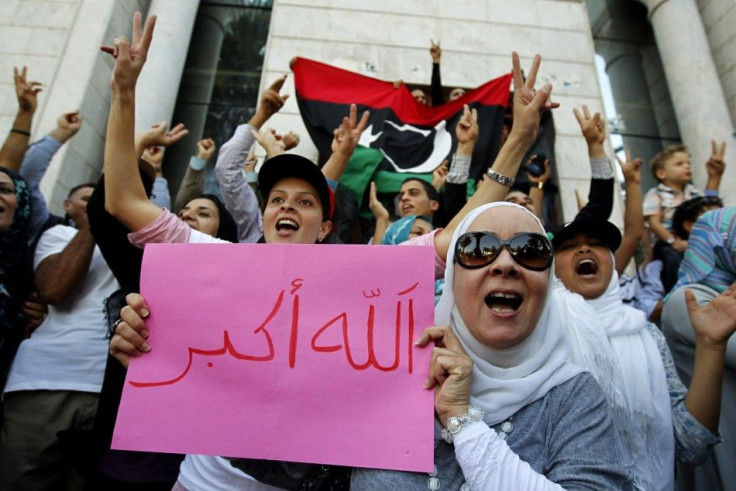 Libyan refugees in Tunisia celebrate after hearing news that Libyan leader Muammar Gaddafi was killed in Sirte, outside their embassy in Tunis