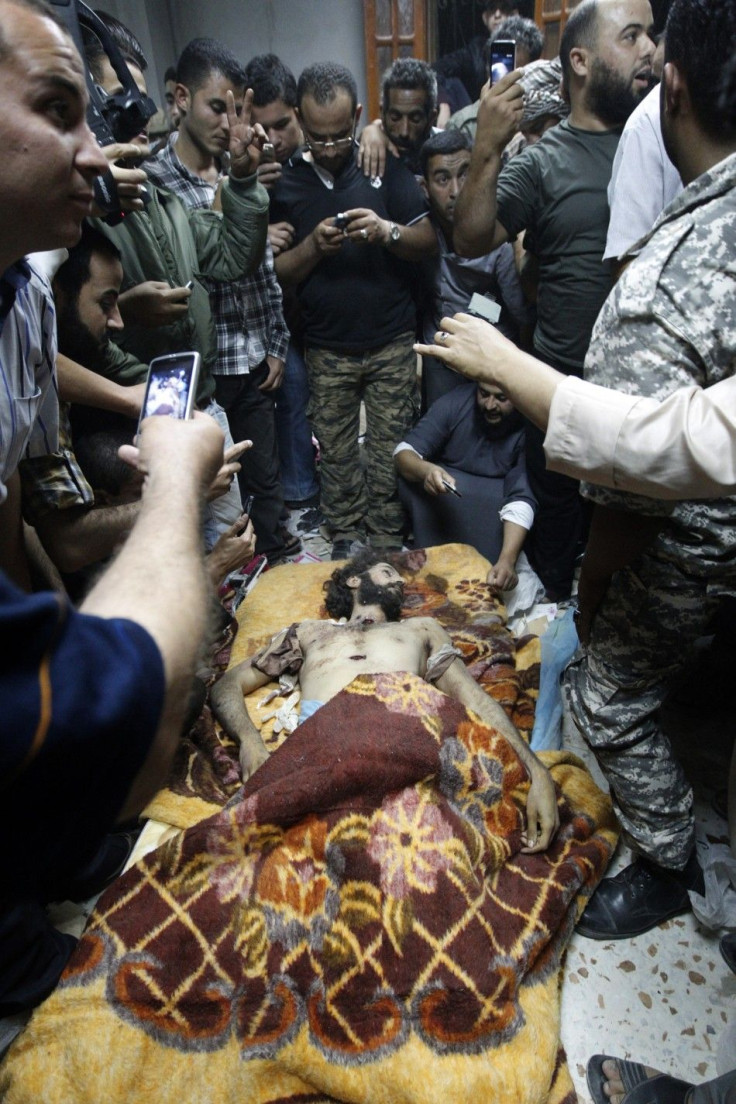 Men stand around and take pictures of Mo&#039;tassim Gaddafi, son of Muammar Gaddafi, in Misrata after being captured and killed during clashes with anti-Gaddafi fighters in Sirte October 20, 2011.