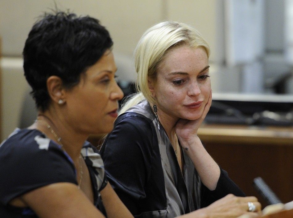 Actress Lindsay Lohan sits in court with her lawyer Shawn Chapman Holley, during a compliance check to report her progress on 480 hours of community service she must do for shoplifting a necklace from a Venice jeweler, in Los Angeles