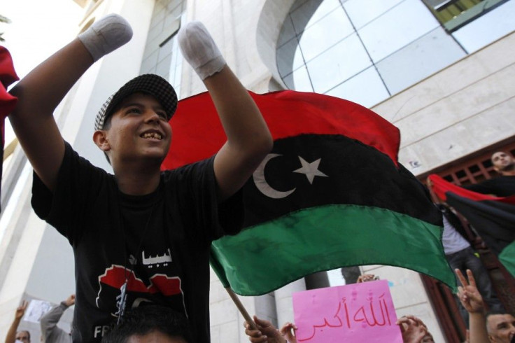 An injured anti-Gaddafi fighter celebrates after hearing news that Libyan leader Muammar Gaddafi was killed in Sirte, outside their embassy in Tunis 