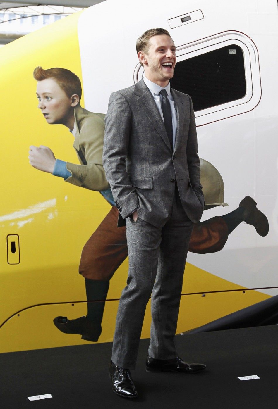 Actor Jamie Bell stands next to a figure of Tintin painted on a Thalys high-speed train in Brussels