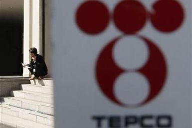 A man is seen behind the logo of TEPCO at the company's headquarters in Tokyo