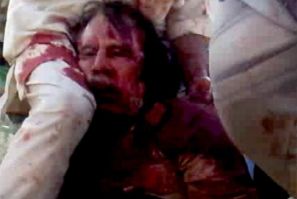 Frame grab of former Libyan leader Moammar Gadhafi, covered in blood, being held on the ground by NTC fighters in Sirte