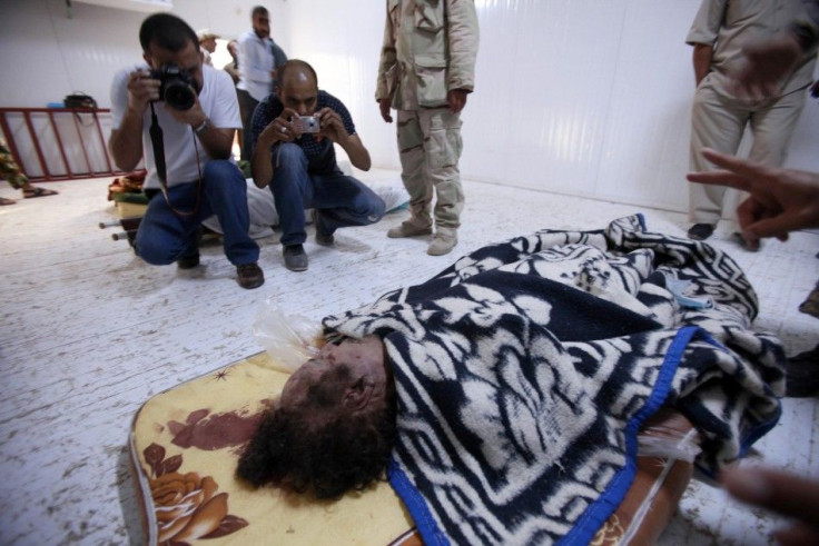 People take pictures of the body of former Libyan leader Muammar Gaddafi inside a meat locker in Misrata